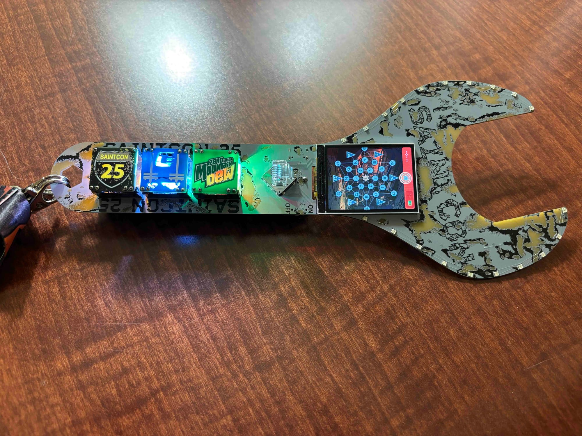 printed circuit board in the shape of a wrench with LEDs shining through smaller circuit boards